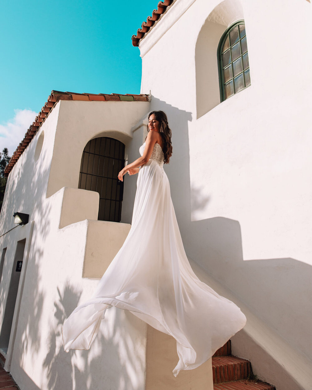 Model wearing Stella York style 7813: a romantic soft a-line wedding dress featuring a sheer lace bodice with a softly scooped neckline, long blouson sleeves detached, and a flowing cotton chiffon skirt