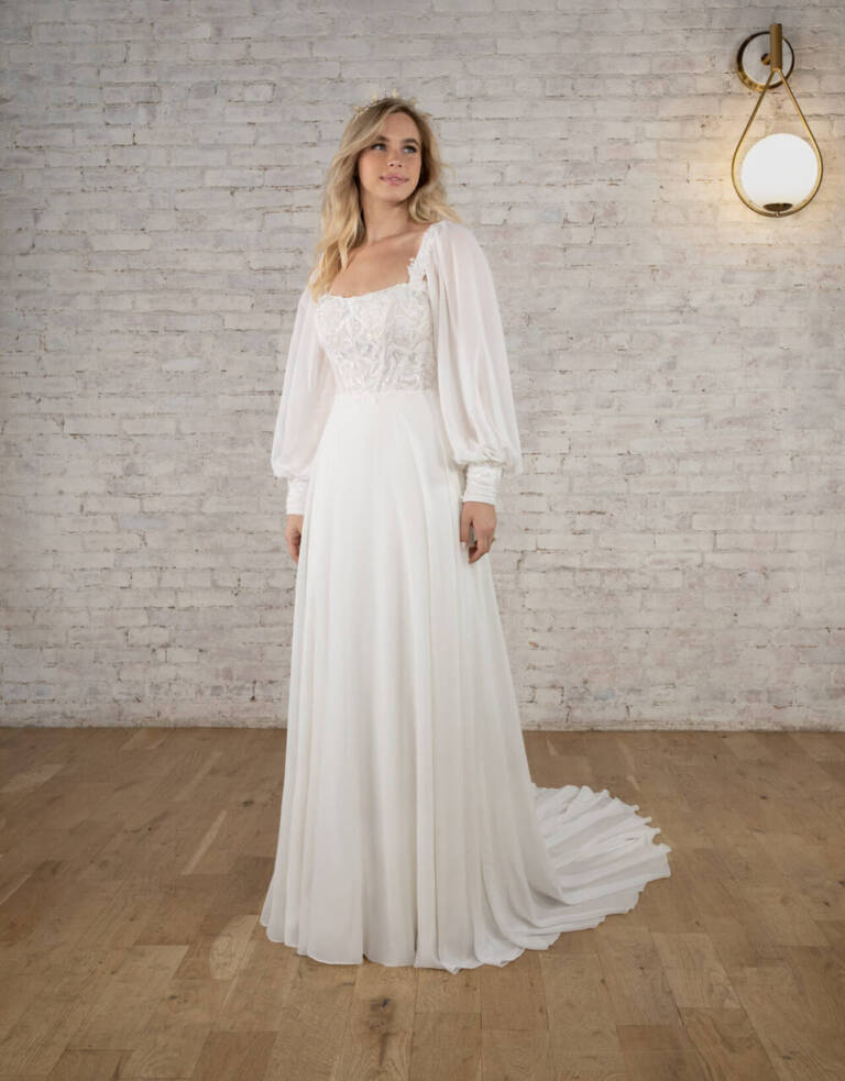 Stella York 7813 ivory wedding dress with sheer lace bodice, detachable long sleeves, soft scoop neckline and flowing chiffon A-line skirt.