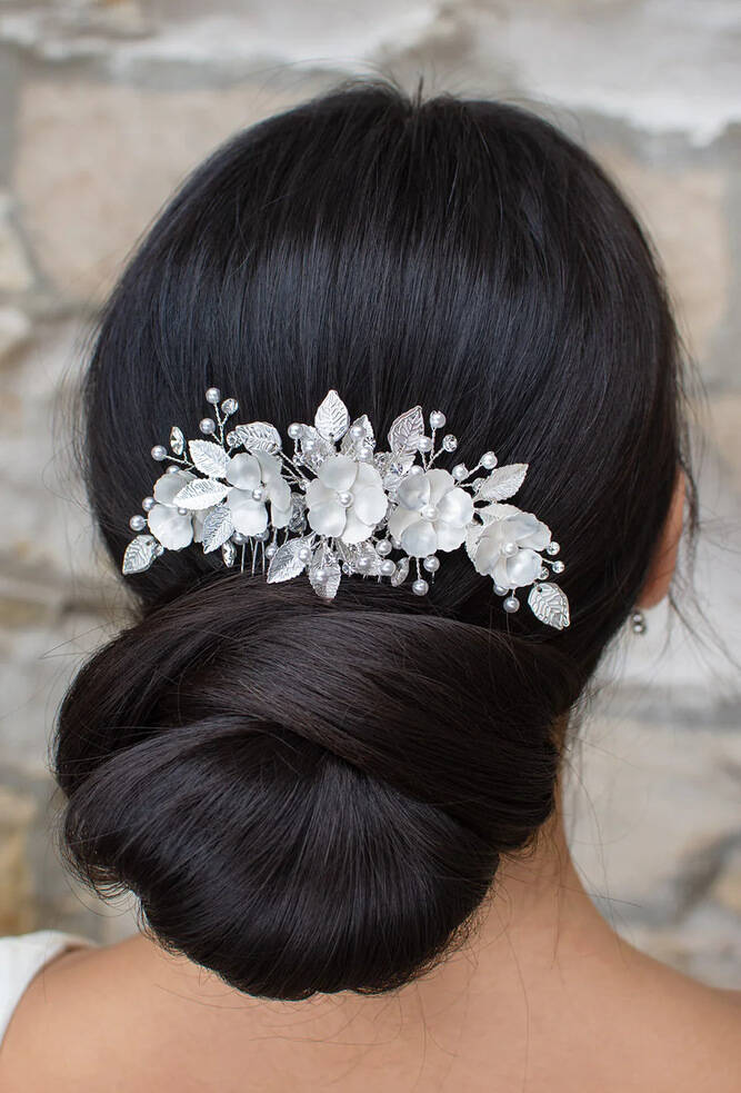 Back view of a bride with a low bun wearing the Ava WF517 bridal side comb—white-silver flowers with crystal accents and pearl sprigs in an arched design.
