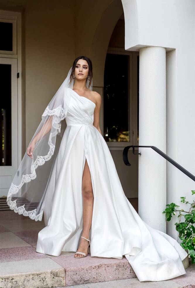 beautiful bride wearing a one shoulder wedding dress with a dreamtime designs veil. The Erica 2 tier veil in a soft tulle edge in a french chantilly lace