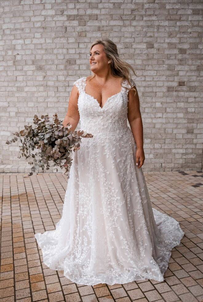 Bride wearing the RSVP "Honour" wedding dress with floral lace detail, sweetheart neckline, and cap sleeves, holding a bouquet of dried foliage.