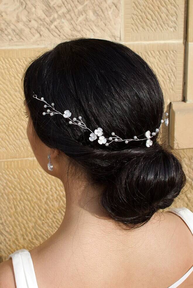 Back view of bride wearing Eleanor Pearl Vine WV208 silver pearl vine hairpiece with small pearls and ceramic flower details, styled over a low bun.