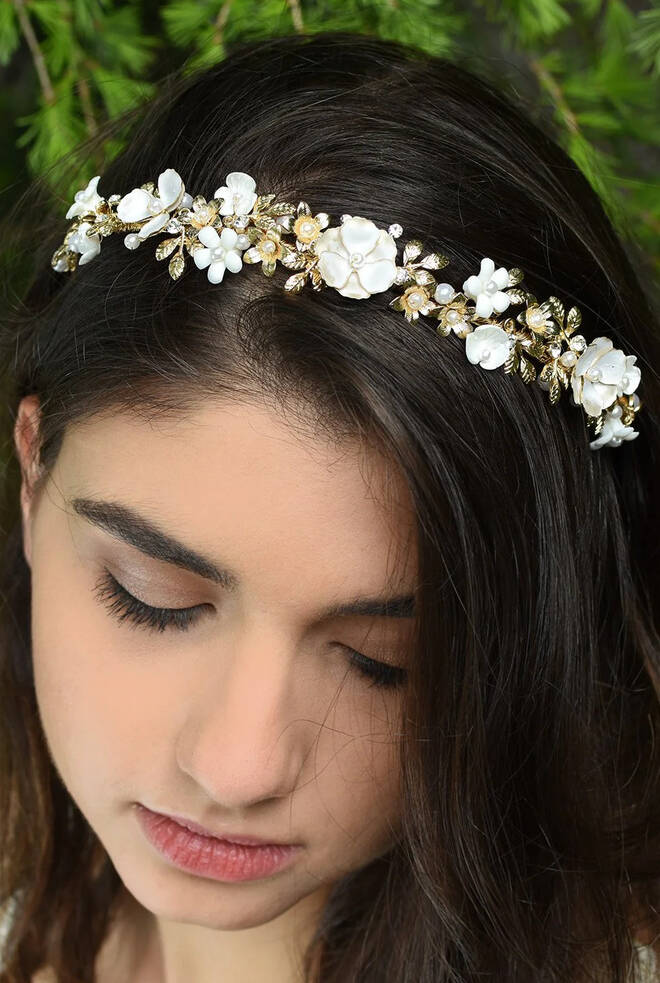 Bride wearing Elodie Floral Headband WH518 in soft gold with pearlised white flowers and metallic leaf detailing across the crown.