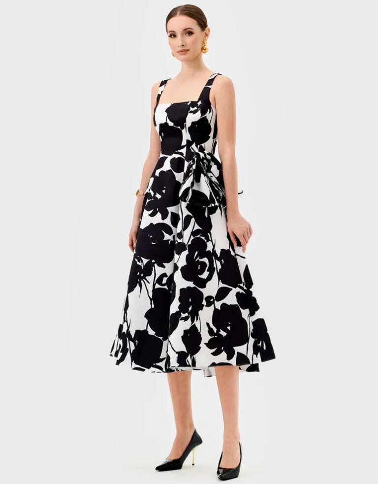 Model wearing Bariano Brittany BL81D03S black-and-white floral midi dress with square neckline, wide straps, A-line skirt and pockets, styled with black heels.
