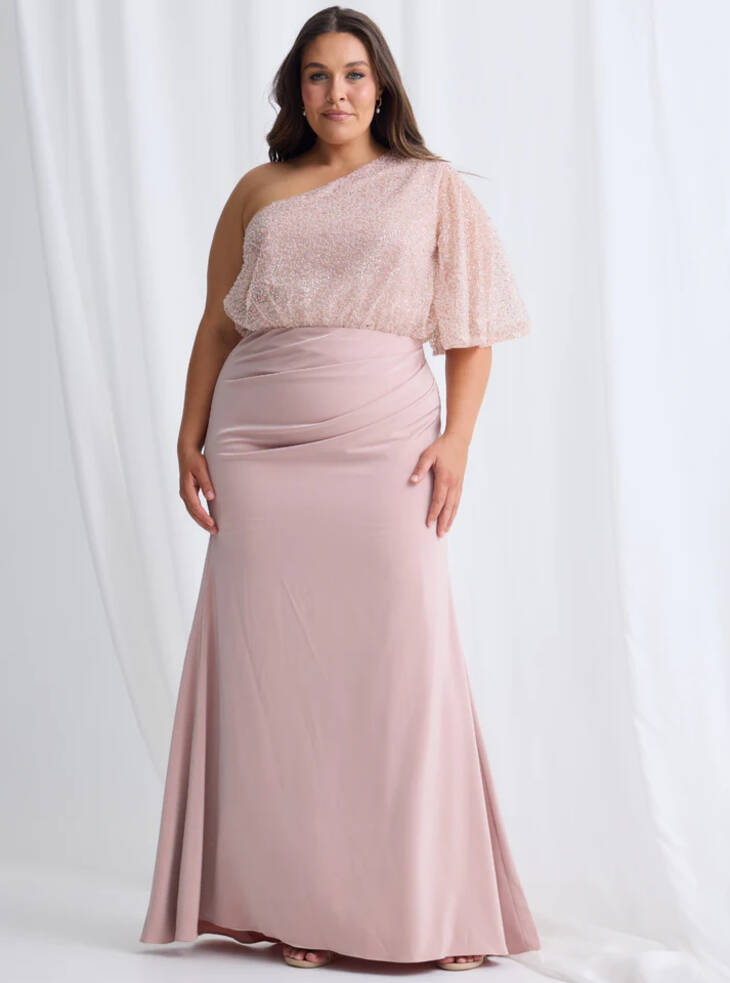 Colleen one-shoulder evening gown in blush with shimmer blouson bodice, flutter sleeve, ruched waist and floor-length skirt on model, front view.