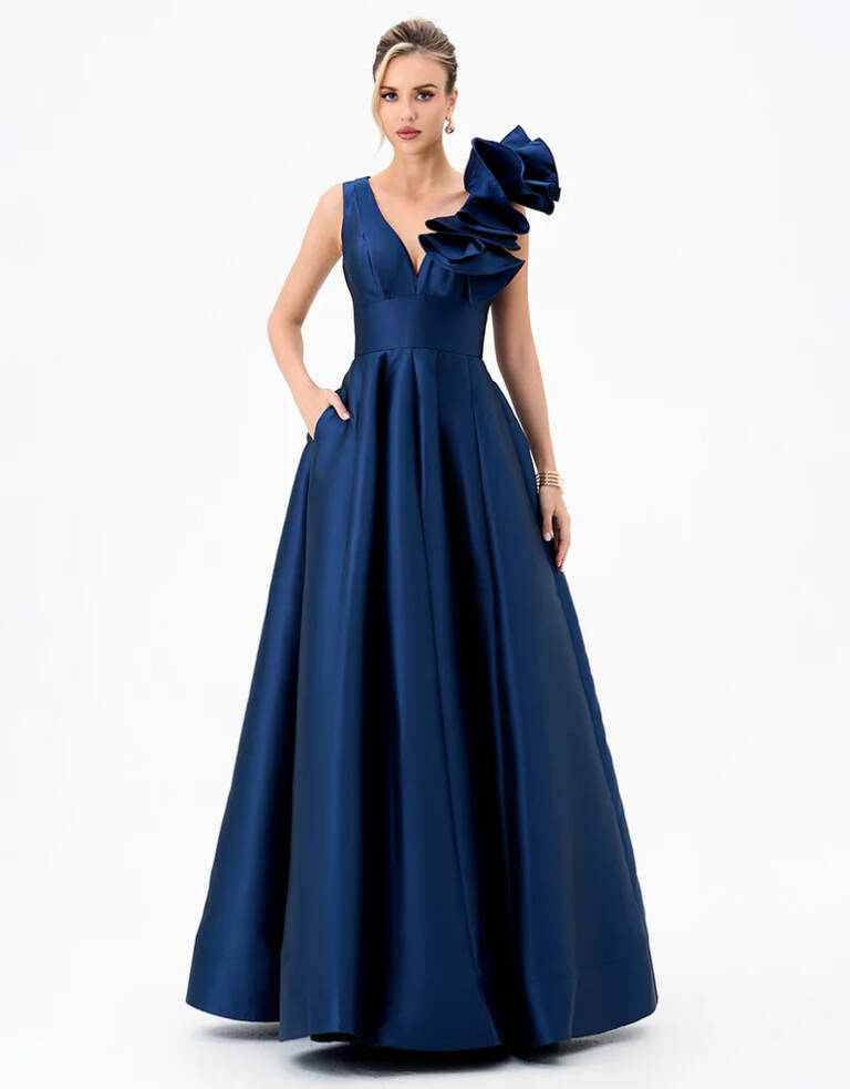Front view of the Mirella V-Neck Ruffle Gown B81D51L by Bariano in navy, featuring plunging V neckline, sculptural one-shoulder ruffle and full A-line skirt, available at RSVP Bridal & Formal