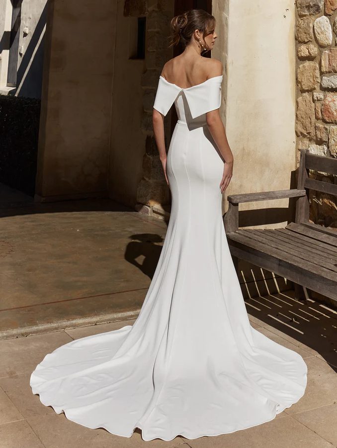 Back view of the Abbie TC2639 wedding dress by Tania Olsen Designs featuring an off-the-shoulder back detail, fitted stretch crepe silhouette, invisible zipper, and a dramatic cathedral-length train.