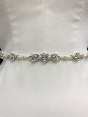 Bride wearing an ivory wedding dress with the Elvis pearl and crystal bridal belt in silver tone, featuring a slim beaded appliqué at the waist. By Peter Trends Bridal