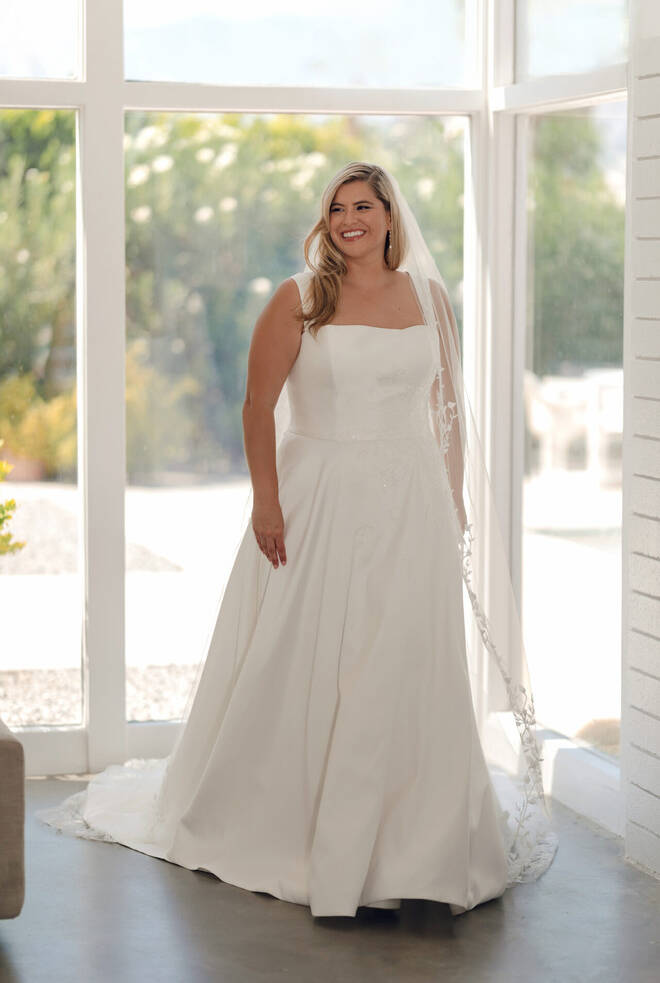 Bride wearing Stella York SY8217+ satin Mikado A-line wedding dress with straight neckline, floral bodice detailing and flowing train.