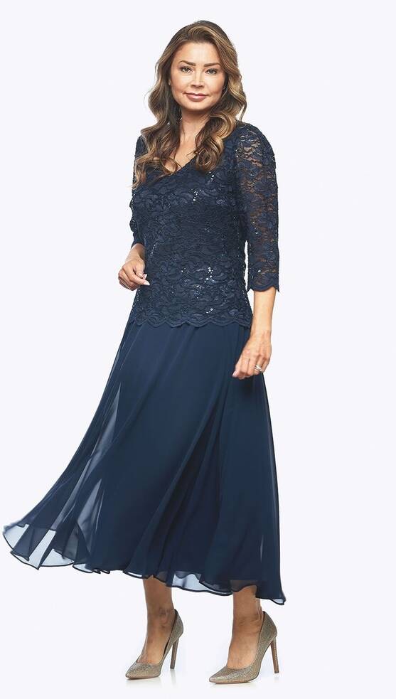 Model wearing the Jesse Harper JH0459 navy embroidered sequin lace and chiffon layered dress with matching jacket, featuring 3/4 lace sleeves and a flowing below-knee chiffon skirt.