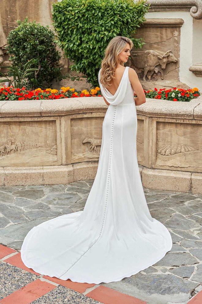 Back view of the Veronica wedding dress showcasing a soft cowl back, fabric-covered buttons and flowing semi-cathedral train.