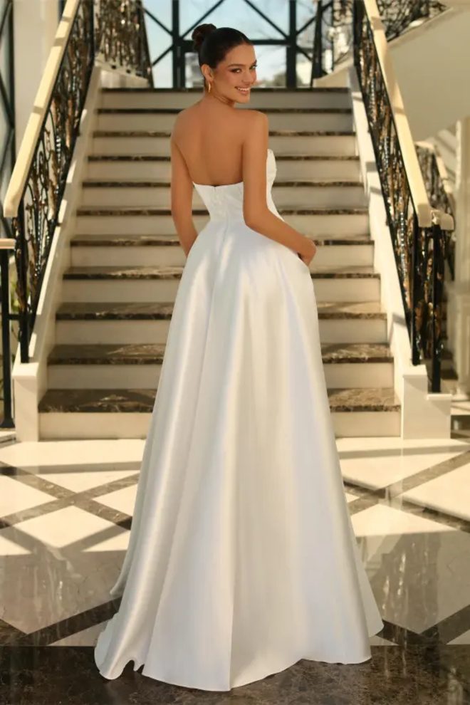 Nicoletta NC1076 ivory Mikado satin wedding dress shown from the back, featuring a strapless pleated bodice and flowing full A-line bridal skirt.